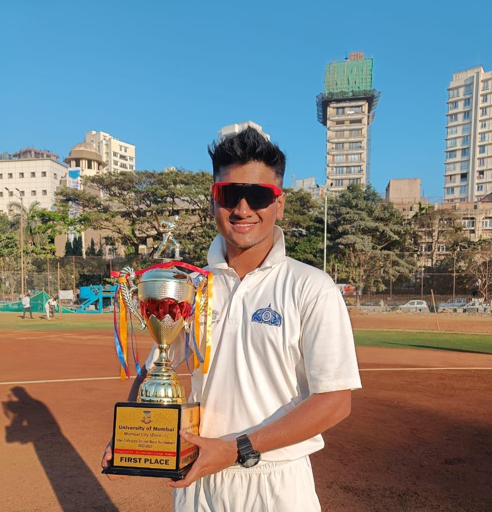Holding the University of Mumbai inter-collegiate first place trophy in cricket whites