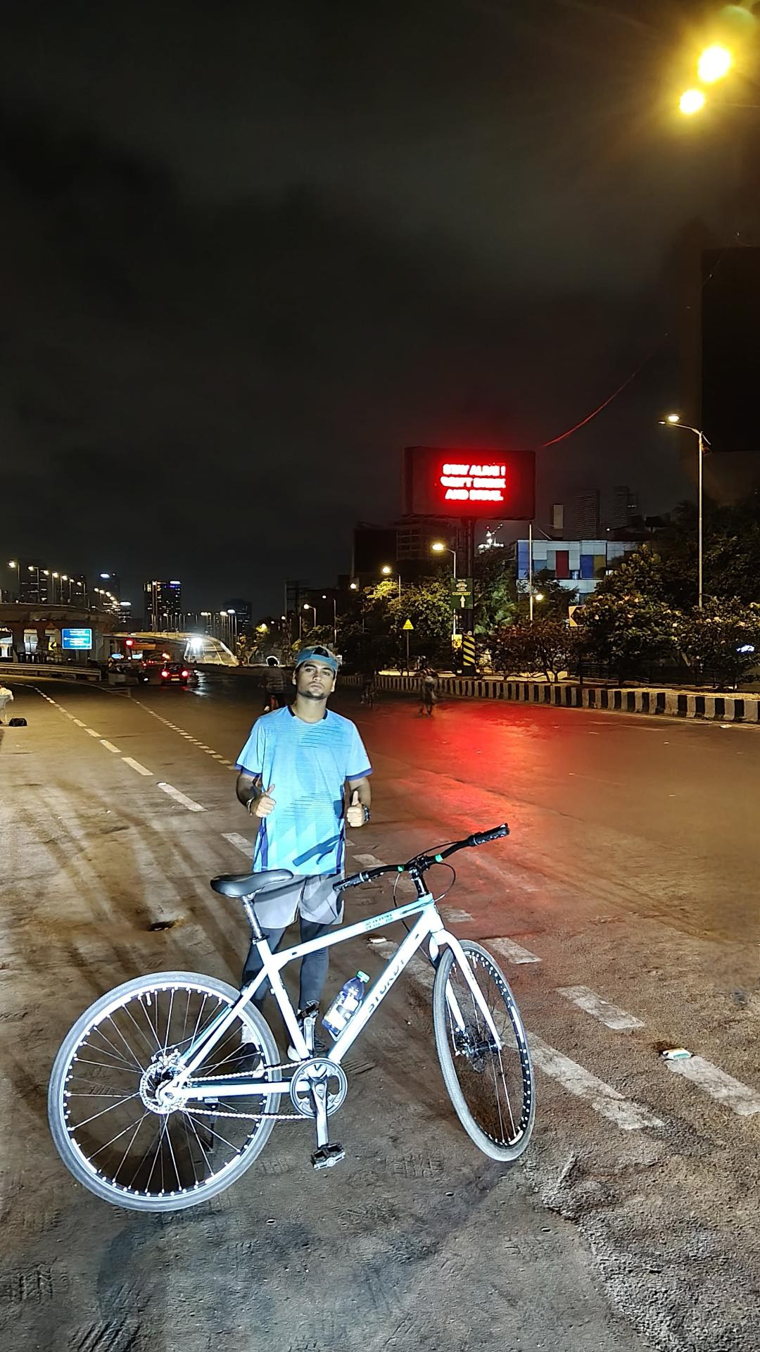 With a bicycle on an empty Mumbai road at night