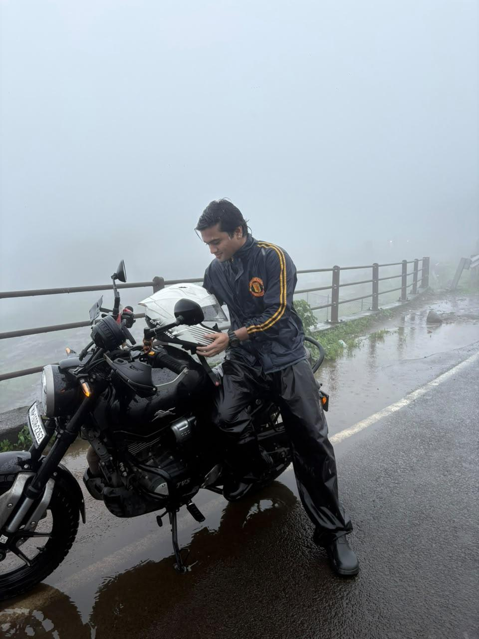 On a motorcycle in full wet-weather gear on a foggy ghat road